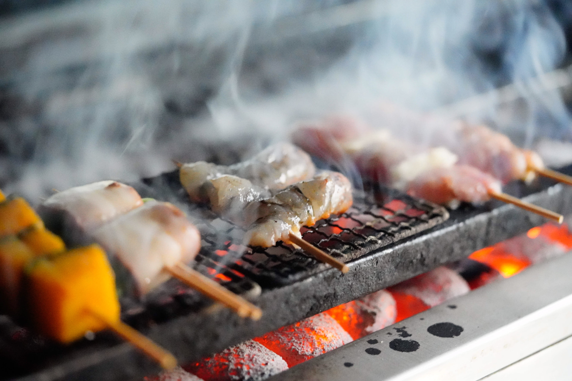 Assorted yakitori skewers grilling over binchotan charcoal