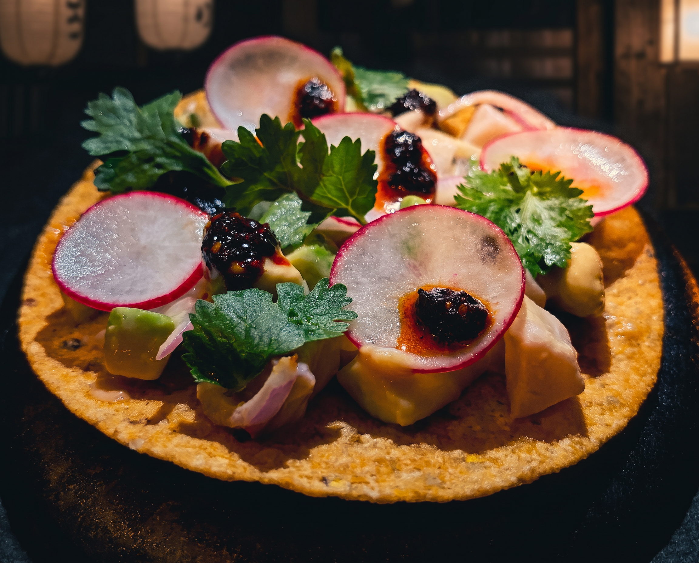 Hamachi ceviche tostada topped with radish, cilantro and salsa macha